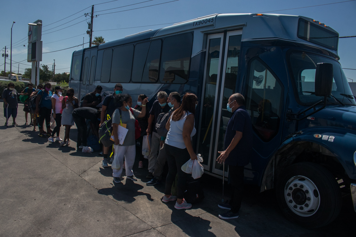 Migrantes, entre ellos abuelos migrantes esperan autobús que los lleva a San Antonio, Texas