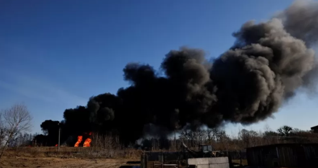 Una columna de humo se eleva desde tanques de combustible en llamas que, según los locales, fueron alcanzados por cinco cohetes en la base aérea de Vasylkiv, en las afueras de Kiev este 12 de marzo.