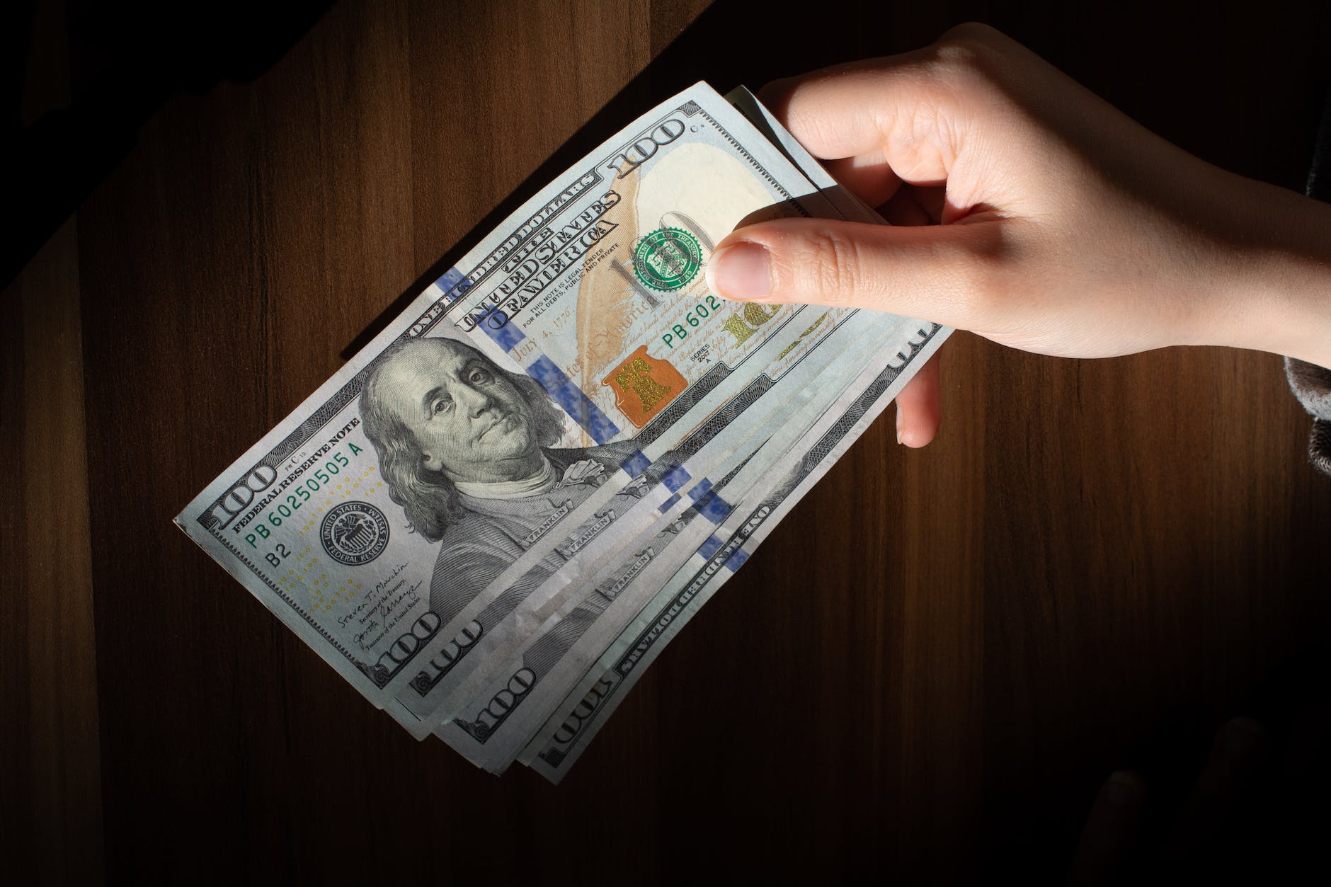 a person holding a stack of money on a table